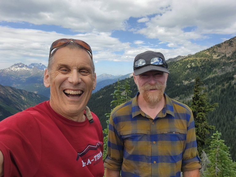 Craig's been recognized by hikers all across the map — even on some of the loneliest trails of North Cascades National Park. Photo by Craig Romano Two hikers smile from the mountains.