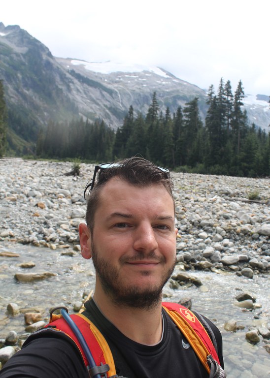 A photo of Wes Partch near a stony river.
