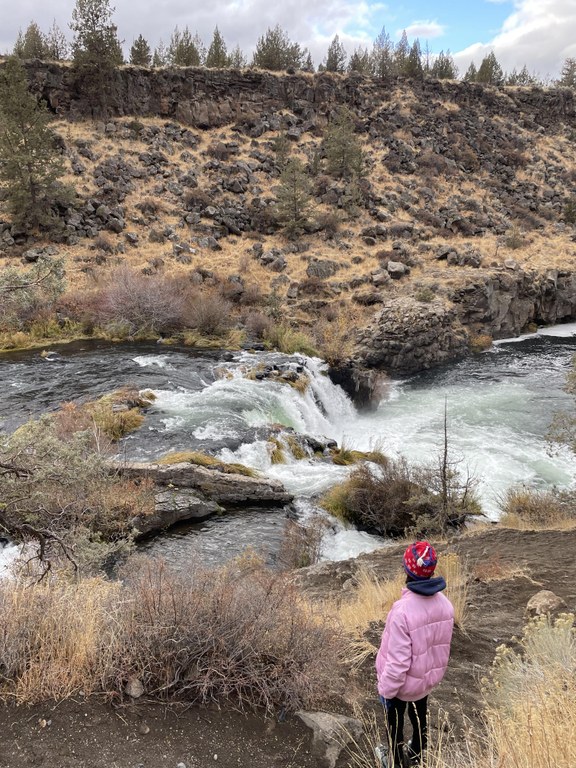 A hiker looks out over a river in a desert canyon.