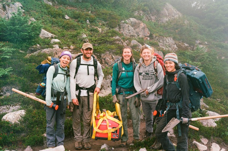 Soon the paid crews will end their season and rest. The 2025 season will pick up again in the spring, with hiring ongoing this fall. Photo by Joe Hall LTF crew members stand with backpacks and tools in their hands on a foggy day.