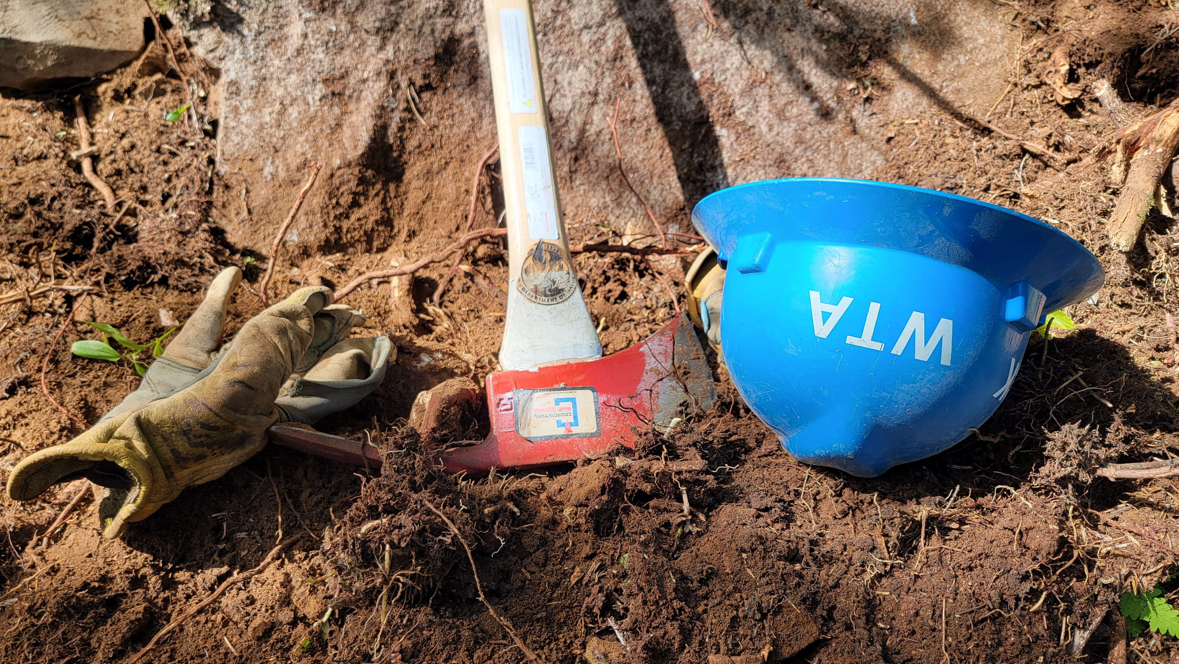 Just like how each tool is best for a specific job, each crewmember brings a unique set of skills to the program. Photo by Joseph Gonzalez A pair of gloves, a pulaski and a blue hat sit in the soil.