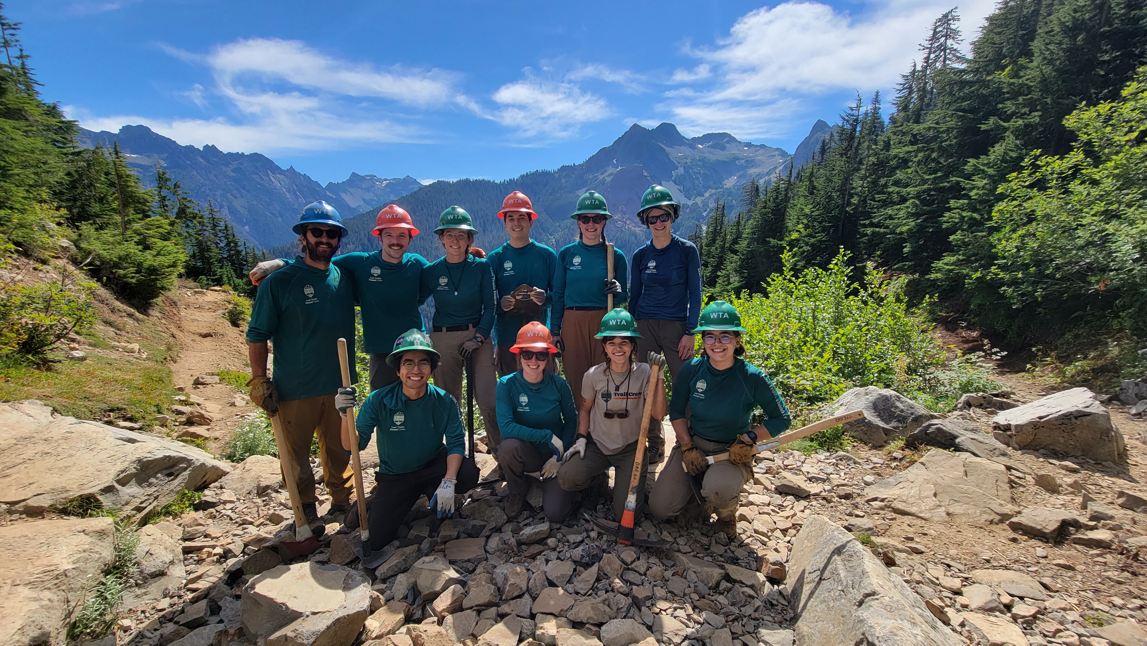 Lost Trails Found crews join forces in the backcountry. Photo by Joseph Gonzalez Lost Trails Found crewmembers pose for a photo before a mountain backdrop.