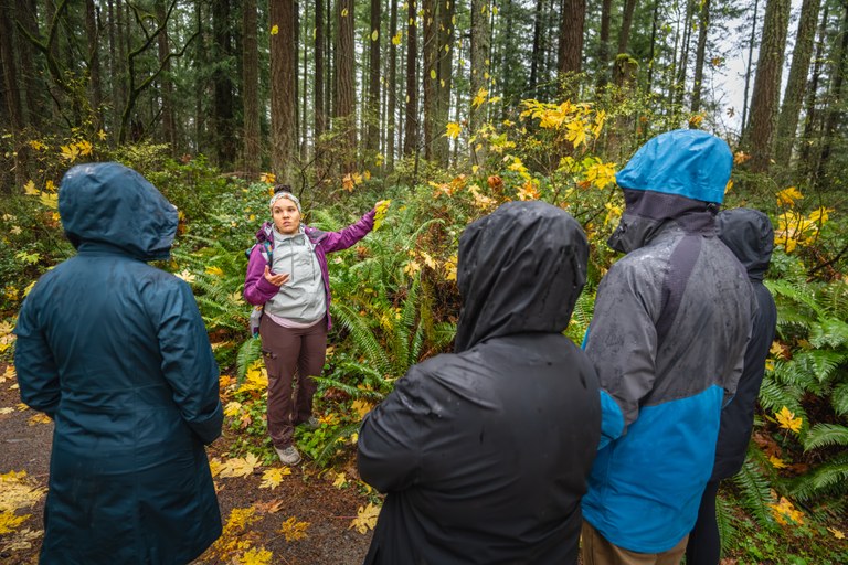 Rachel stands next to plants showing them to a group of three people