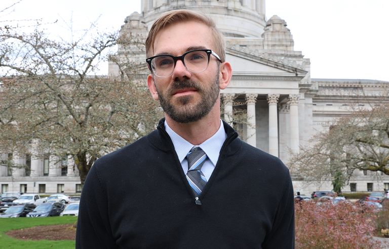 Alan Jircik A hiker in shirt and tie stands in front of the state capitol.
