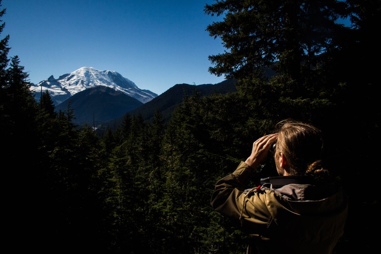 A hiker looking through binoculars. 