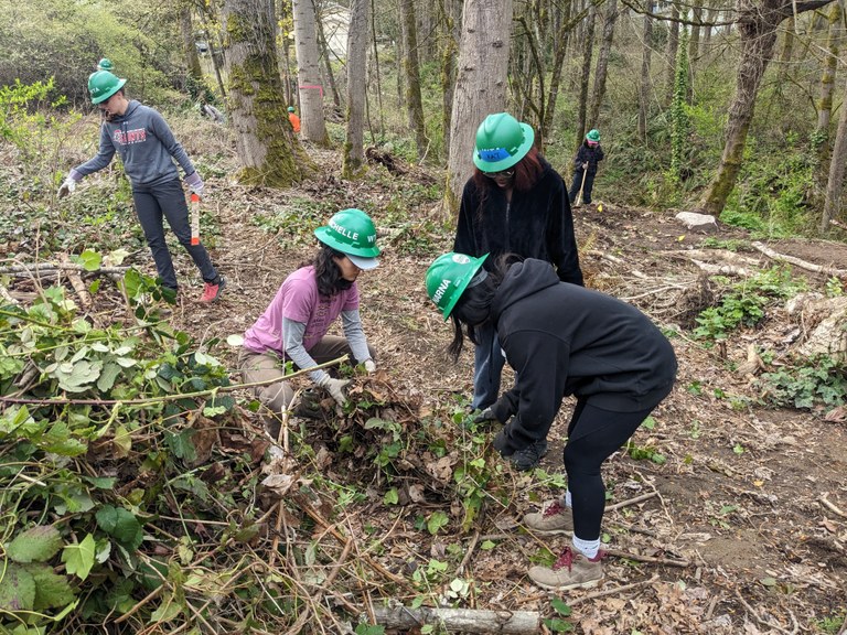 Youth volunteers work together to bundle a pile of trail debris.