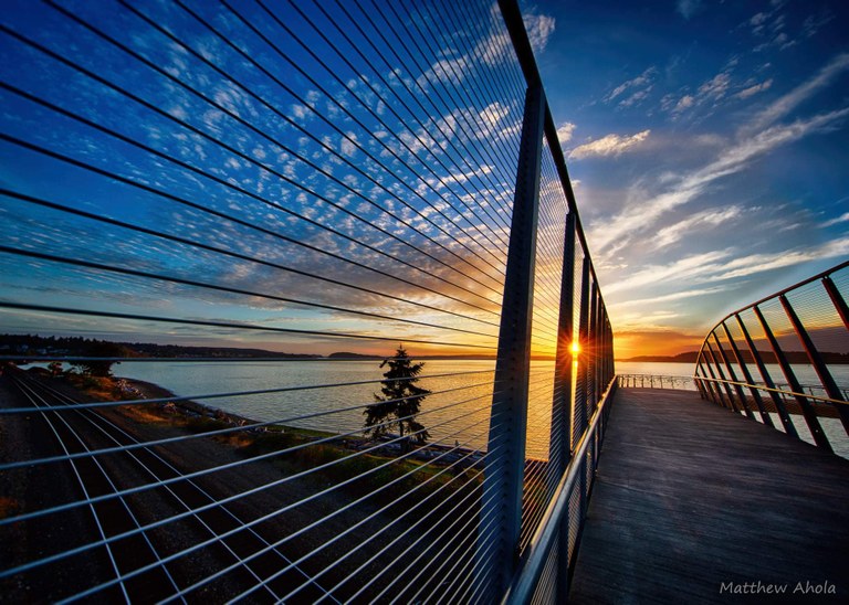 Sky bridge over the train tracks leading to the waterfront at sunset.