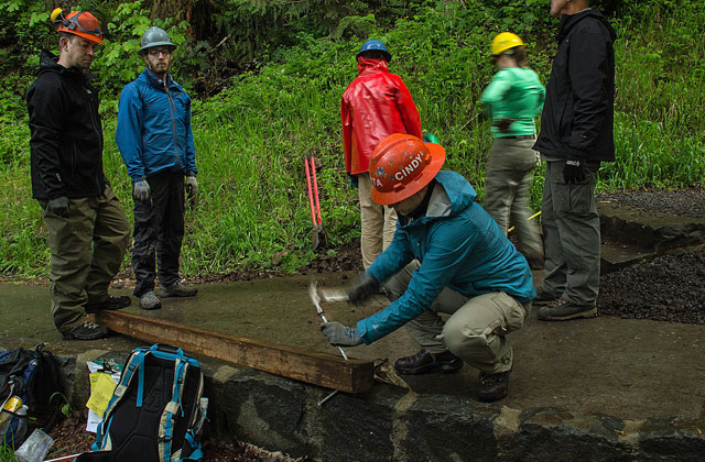 Cindy sporting a seasoned hard hat, participates in a sign installation course at 2016 Trail Skills College. Photo by Gray Feather Photography. 