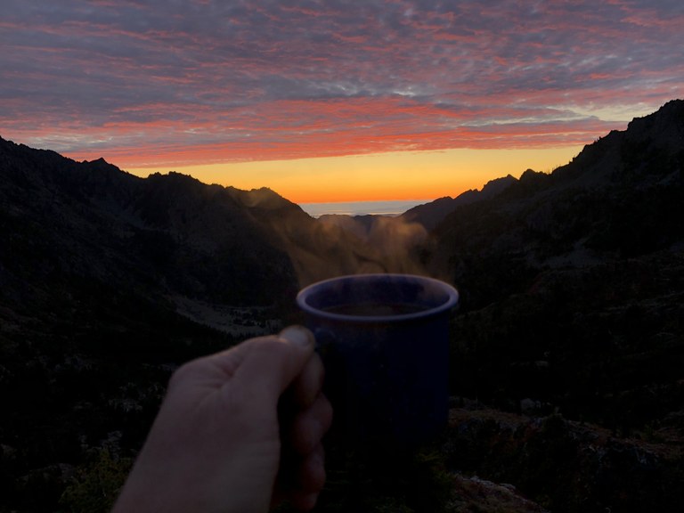 A cup of coffee held up to a sunset.
