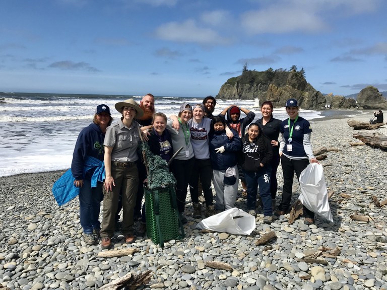 The Deaf T-Birds smiling at Ruby Beach while holding trash bags.