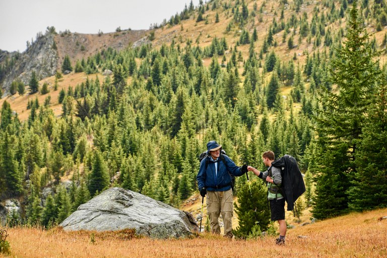 Nathan and Chuck fist bump to show support after a tough climb. Photo by Doug Diekema. Two hikers fist bump to show support after a tough climb. They wear backpacks on a mountain ridge. Photo by Doug Diekema.