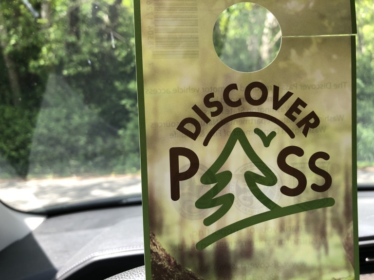 A photo of a Discover Pass with greenery in the background. 