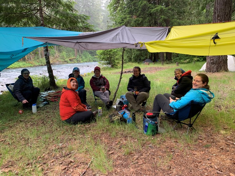 Volunteer crew sits under multiple tarps on a rainy day along the Dosewallips River Road trail on an intro BCRT. Photo by Jennifer Kelley.