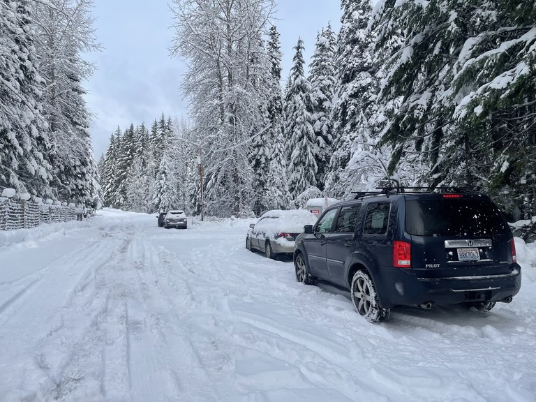 Cars parked alongside a snowy road at a trail near Seattle.