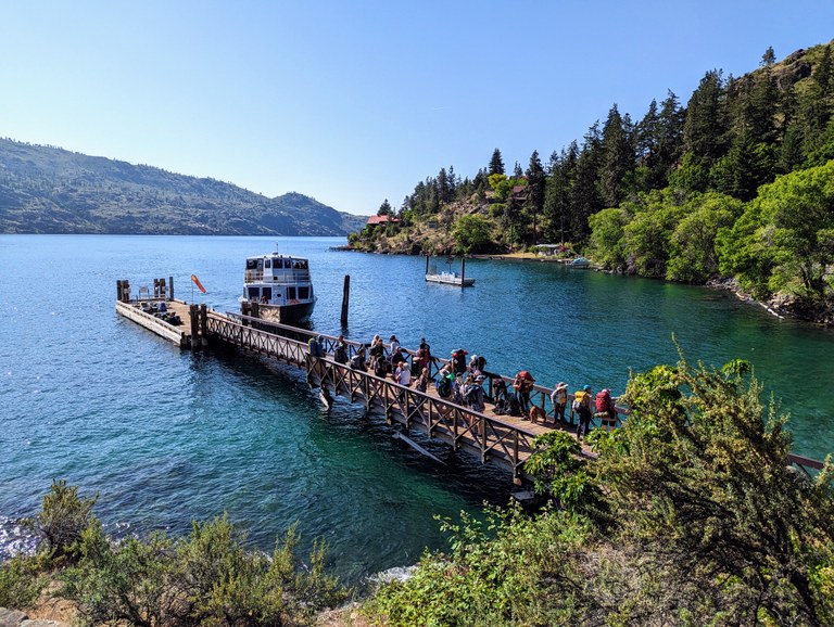 A ferry docks at a floating landing ramp and a crew of a dozen volunteers dismount and head to land. 