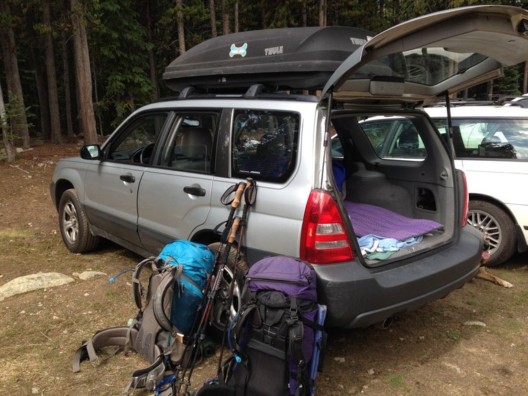 Two backpacks lean against an empty car at the trailhead. Photo by Loren Drummond. 