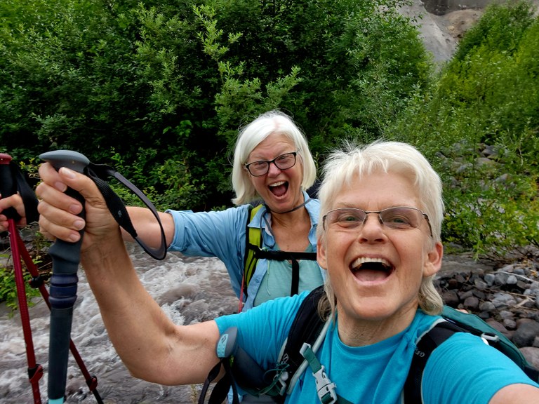 Two hikers smile together for a selfie. 