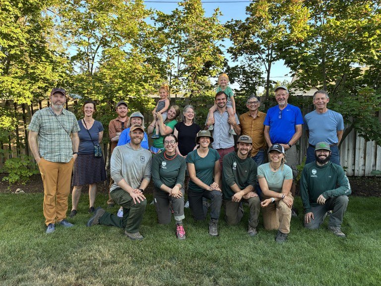 A group of trail advocates pose for a photo on a lawn.