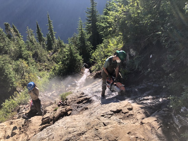 Steps are appreciated by every hiker, especially on steep trails like Gothic Basin. Photo by Zack Sklar. WTA crews use a power tool to cut steps into a rocky trail.