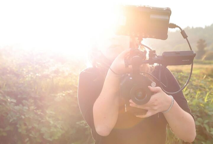 VO filming for Coextinction photo by Elena Jean Sun shinning on right side of photo. Woman holding cinema camera.