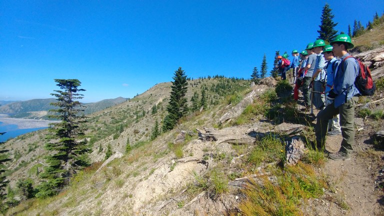 A string of volunteers take in the view on a hillside.