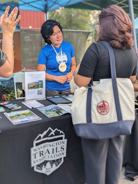 A WTA ambassador in a blue t-shirt talks to event attendees.
