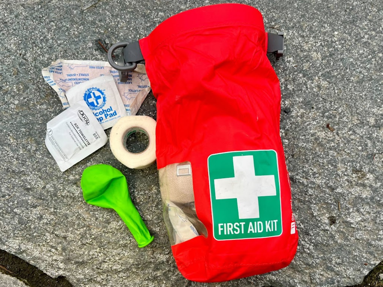 A first aid kit and a green balloon on a rock.