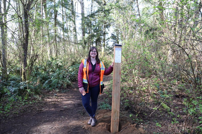 Katherine Phillips, City of Everett program coordinator, with one of the wayfinding signs throughout the trail system. Photo by Victoria Obermeyer.
