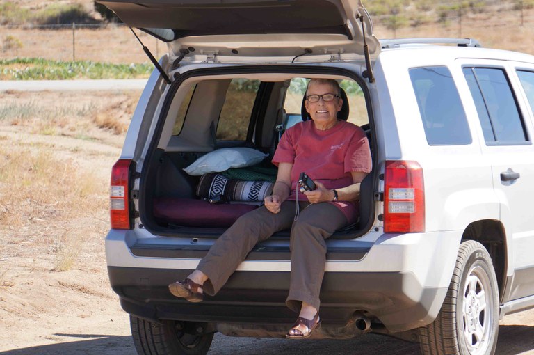 Lezlie's mother sitting in an open car trunk. Photo by Lezlie Cox.