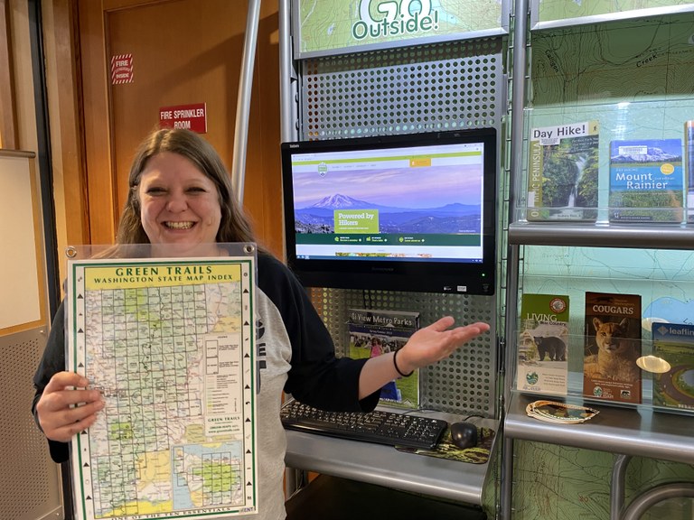 A library employee in North Bend stands in front of the kiosk with information on hiking in Washington.