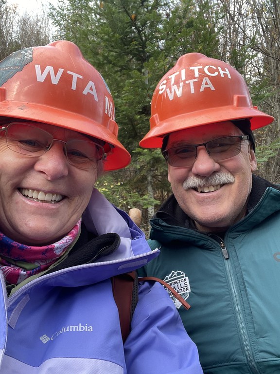 A couple wearing orange hard hats take a selfie. 