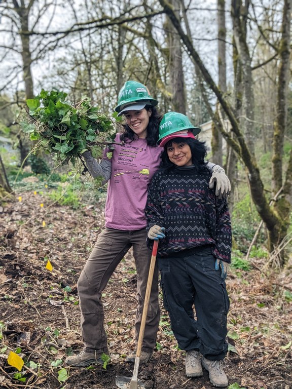 Emerging Leaders Program cohort members stand side by side with tools and trail debris in hand.