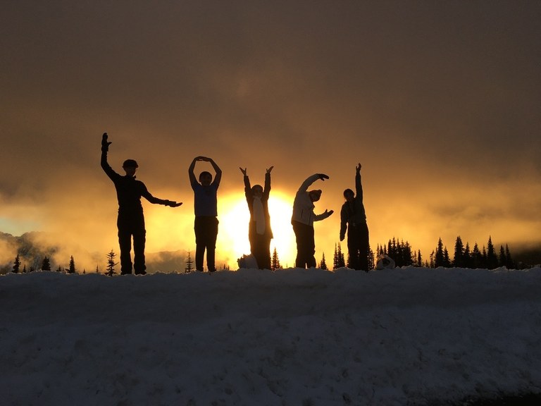 A group of student silhouetted against a bright sunset.
