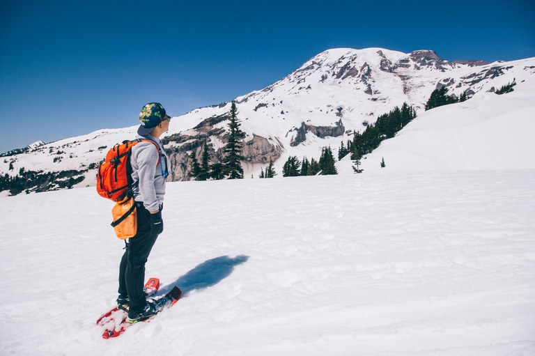 A snowshoer standing in front of Mount Rainier. 