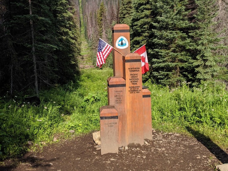 The wooden monument at the northern terminus of the Pacific Crest Trail, on the United States-Canada border. Photo by Tiffany Chou.