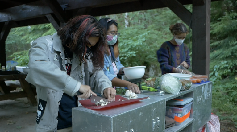 Teens prep a meal together in a backcountry kitchen. 