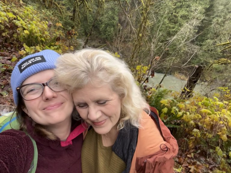 Two hikers take a selfie on a verdant trail.