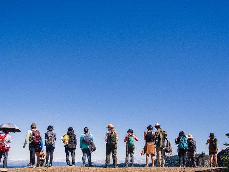 Line of hikers stand on trailside with Park Ranger standing in the middle.