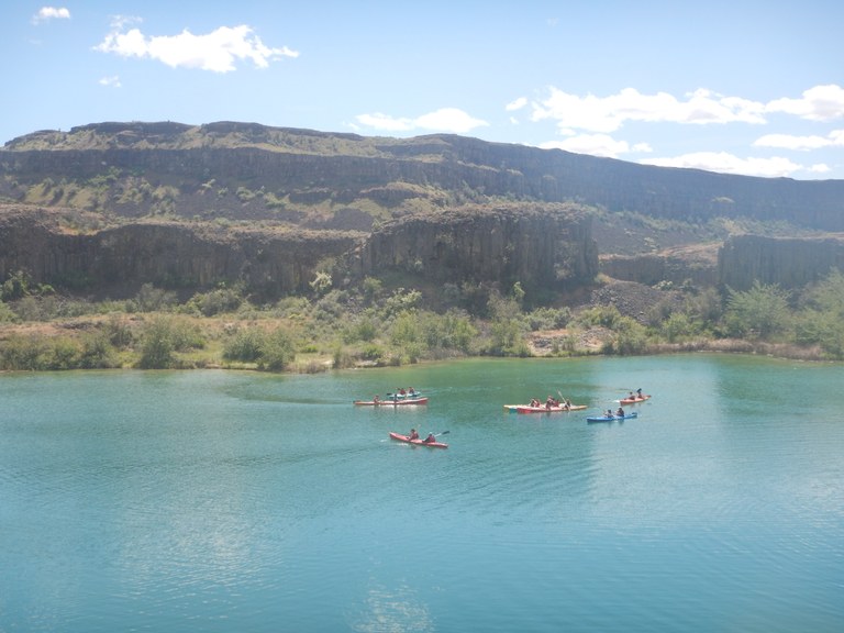 Post 84 kayaking trip Students kayaking in front of tall cliffs.