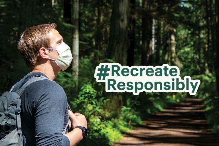 A hiker, wearing a mask, in a green forest with the words #RecreateResponsibily