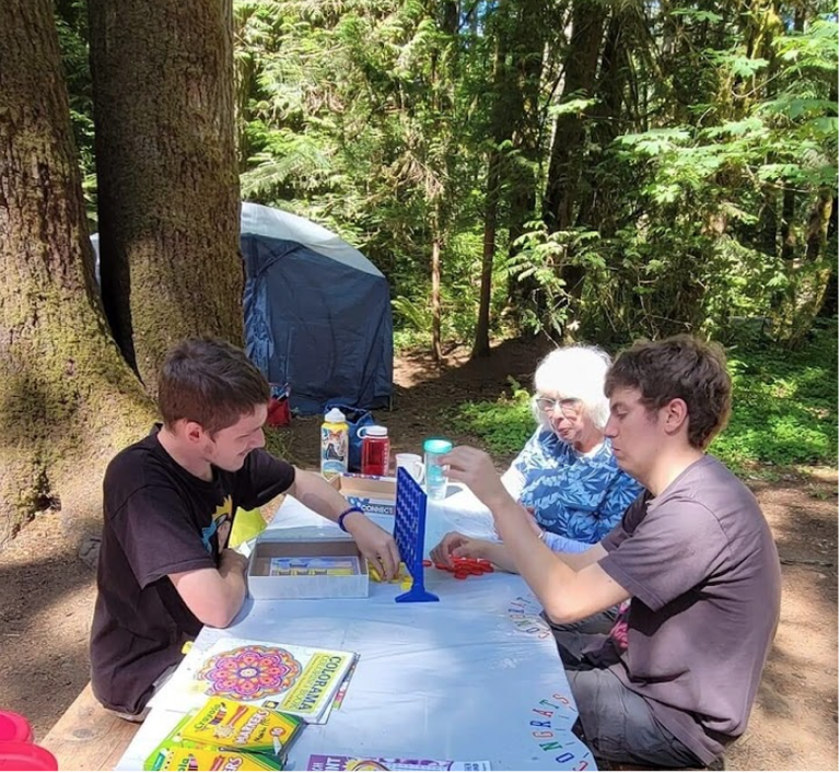 Sequoia Therapeutics Two youth and an older adult play a game at a picnic table.