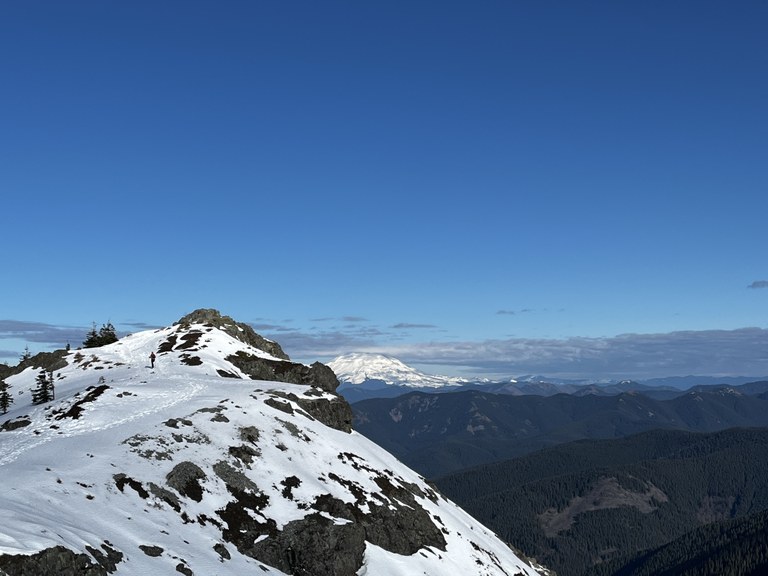 View of Mount St. Helens and a hiker on the snow from Silver Star Mountain trail. Photo by trip reporter clarahikes.