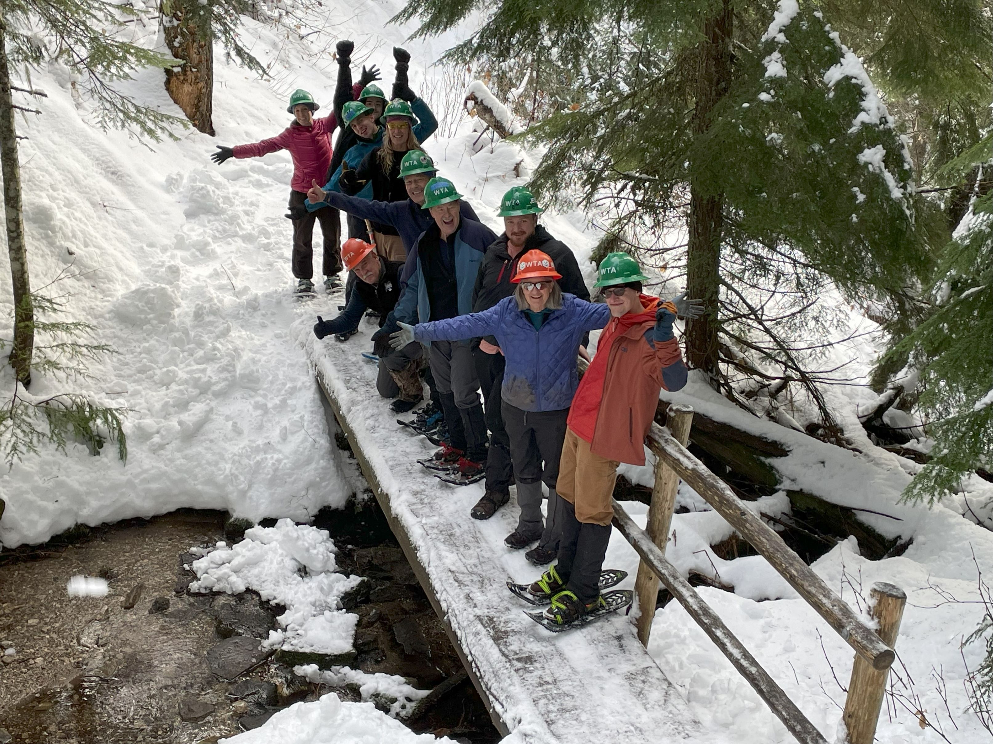 Group of volunteers posed on a snowy bridge on a snowshoe work party in Eastern Washington. Photo by Holly Weiler. 