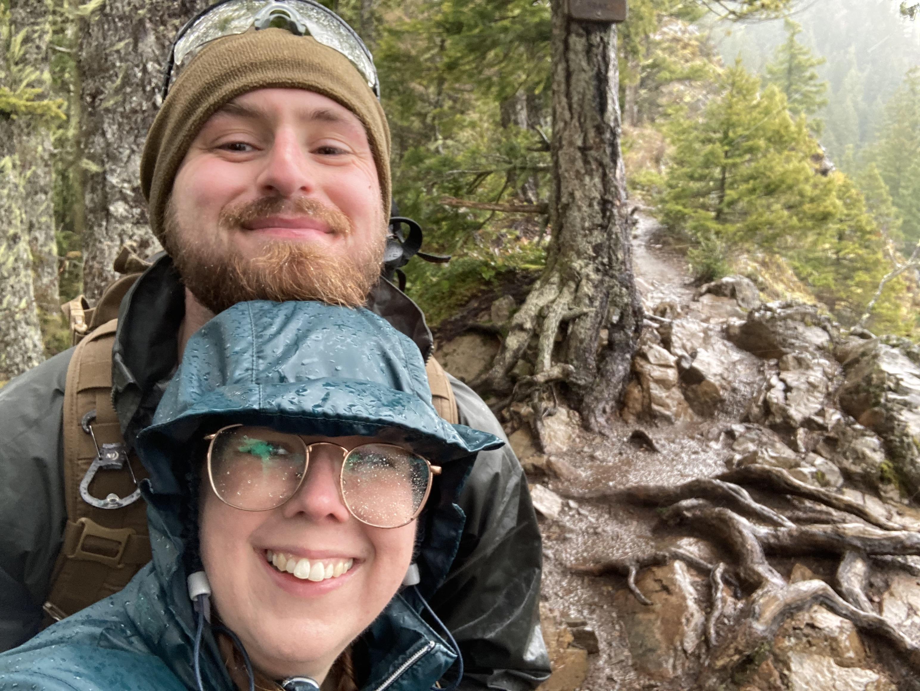 Two smiling hikers take a selfie in the rain
