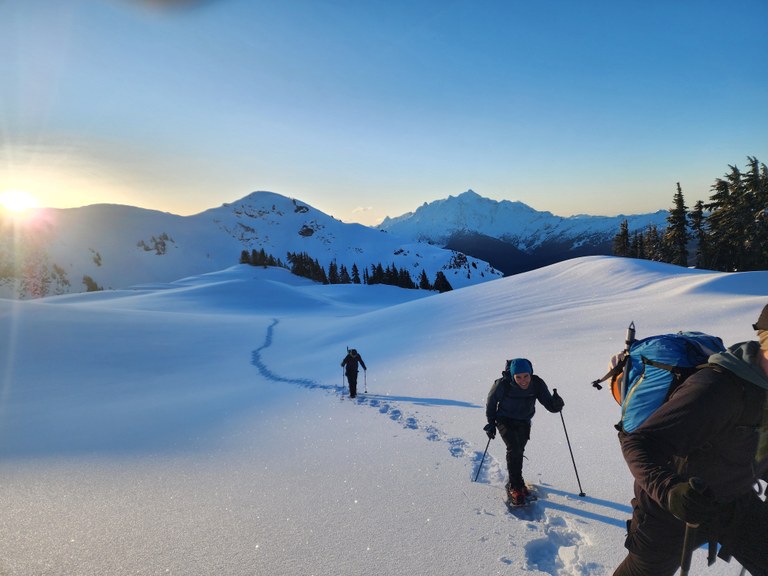 Tomyhoi Peak in the snow. Photo by Alden Ryno.  Three (3) hikers snowshoe in deep snow on Tomyhoi Peak. Photo by Alden Ryno.