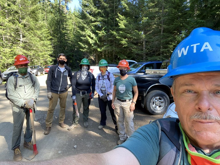 Crew Leader Patrick Sullivan snaps a selfie with his masked-up crew in the background before heading out on a multi-day trip to Marmot Pass. Photo by Patrick Sullivan