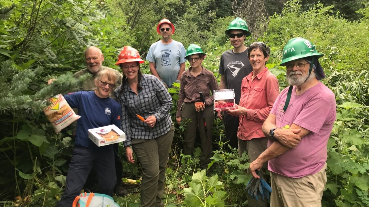 Trails crews recieve trail magic from everyone's favorite Pie Guy! Photo by Erin McMillan Seven people smile at camera. Holding treats on trails.