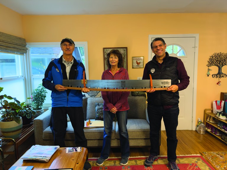 Janice Neumiller (center) honored her parents with a generous gift to WTA. WTA volunteer Jim Scrafford (left) and Jaime Loucky (right), WTA’s CEO, are holding a crosscut saw engraved with Al and Beulah’s names. Photo by Adam Steinberg Three people pose with a crosscut saw.