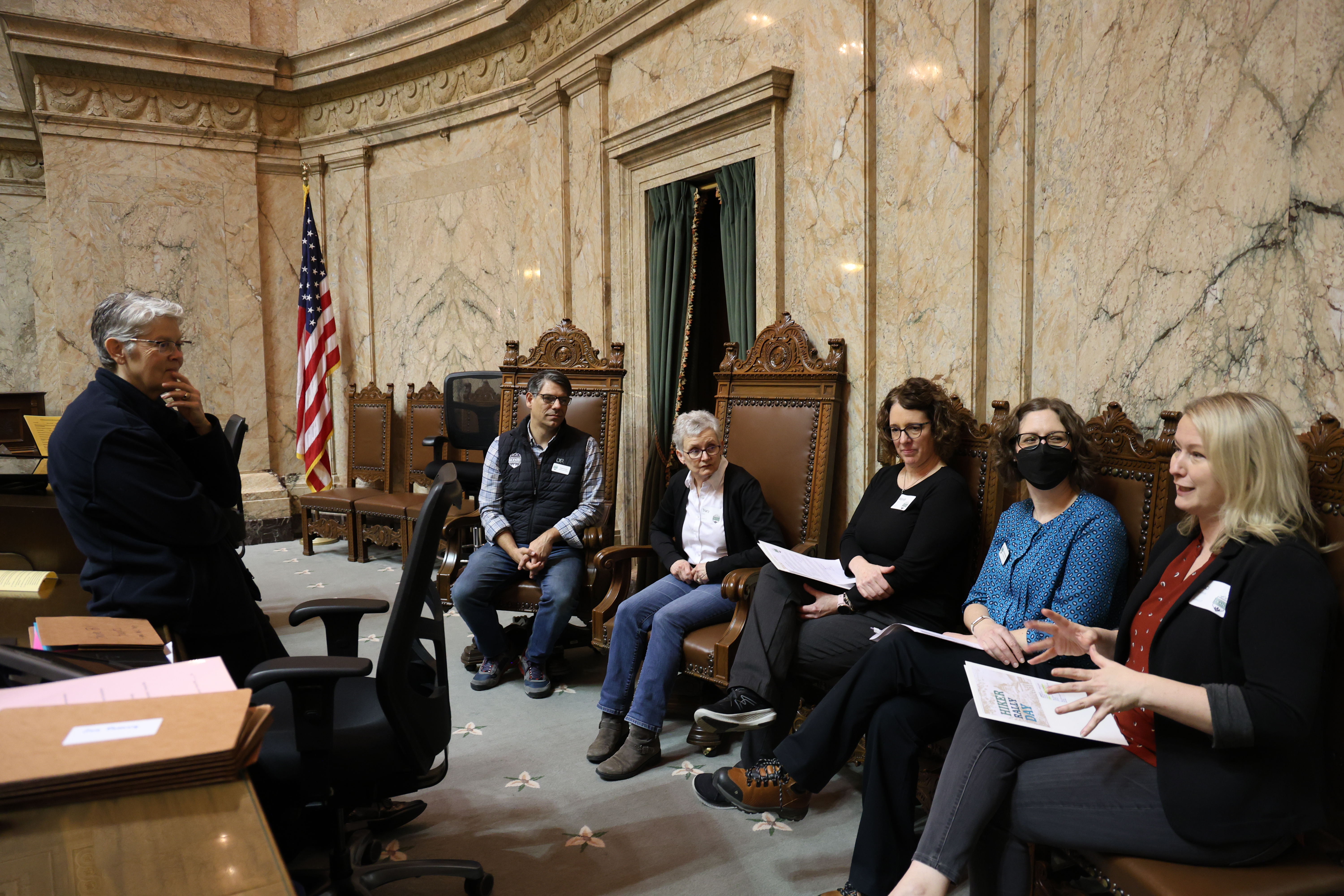 Five people in a marble-walled room talk with Washington state's Speaker of the House