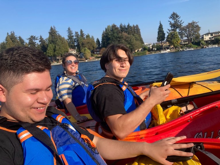 Students in kayaks smile on a sunny day. 